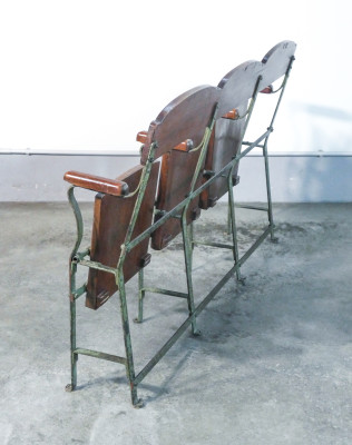 Panca da cinema in legno e metallo, con sedute sollevabili stampate a rilievo, a tre posti. Italia, Anni 40/50