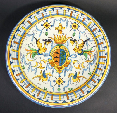 Piatto decorativo in ceramica dipinta a mano con stemma centrale e grottesche, stile Deruta. Italia