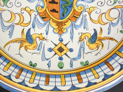 Piatto decorativo in ceramica dipinta a mano con stemma centrale e grottesche, stile Deruta. Italia
