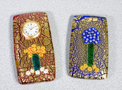 Set da scrivania composto da due fermacarte, uno con orologio, in vetro soffiato policromo, firmato DE WAN. Anni 90