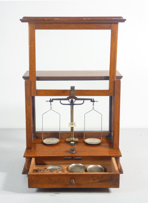 Bilancia da farmacia di precisione, teca in legno, con meccanismo di sollevamento dei piatti, cassetto e pesini. Italia, Fine Ottocento Primo Novecento