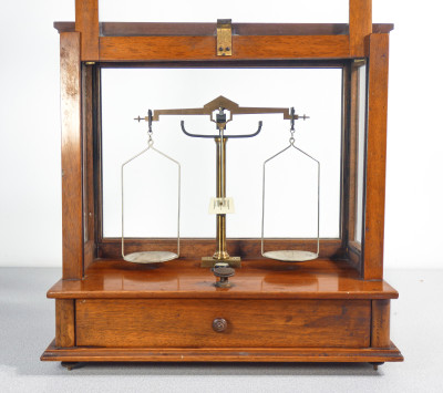 Bilancia da farmacia di precisione, teca in legno, con meccanismo di sollevamento dei piatti, cassetto e pesini. Italia, Fine Ottocento Primo Novecento