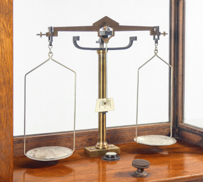 Bilancia da farmacia di precisione, teca in legno, con meccanismo di sollevamento dei piatti, cassetto e pesini. Italia, Fine Ottocento Primo Novecento
