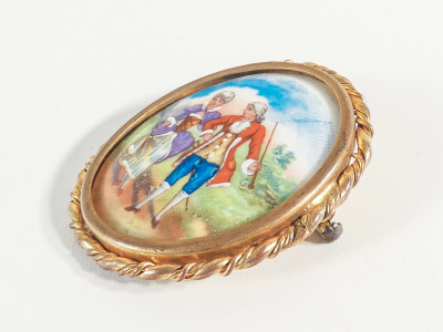 Spilla ovale in ceramica LIMOGES con scena galante in cornice dorata. Francia, Primo Novcento